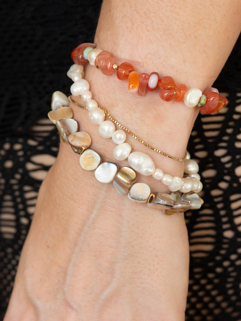 Stack of beaded bracelets on a wrist with a black lace background
