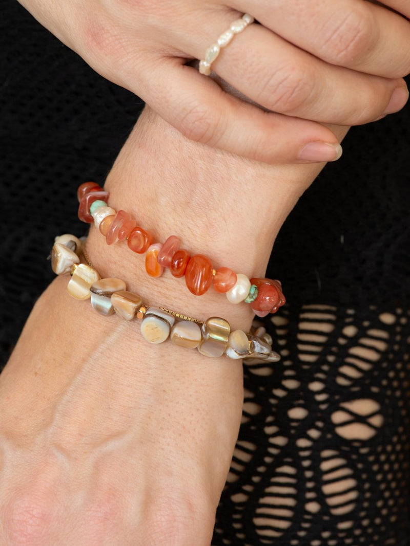 Close-up of a hand wearing two beaded bracelets on a black background