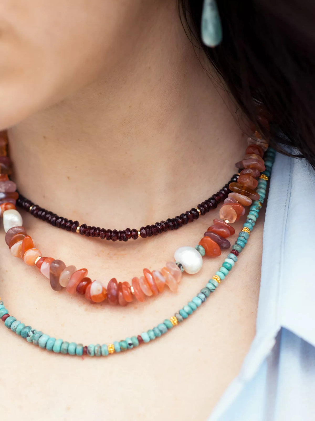 Close-up of a person wearing a colorful beaded necklace with a blurred background