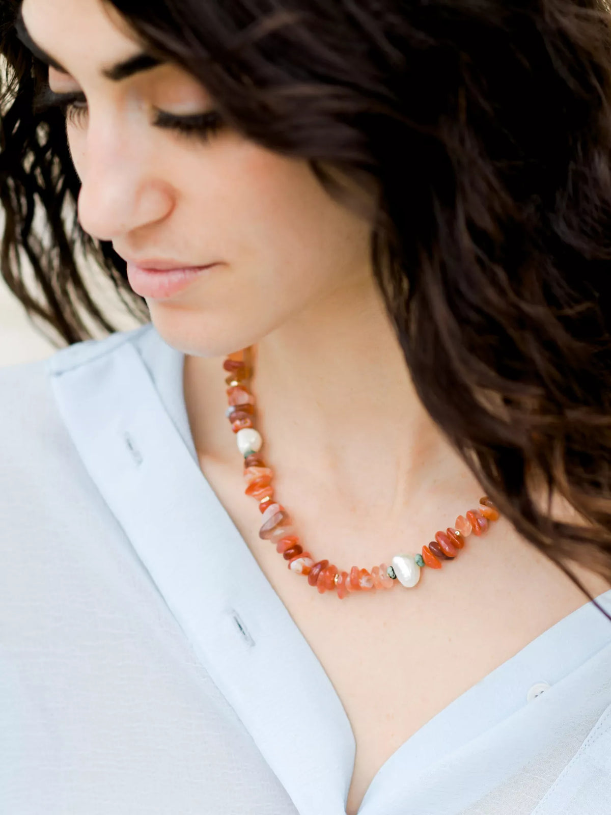 Woman wearing a multi-color beaded necklace with a white background