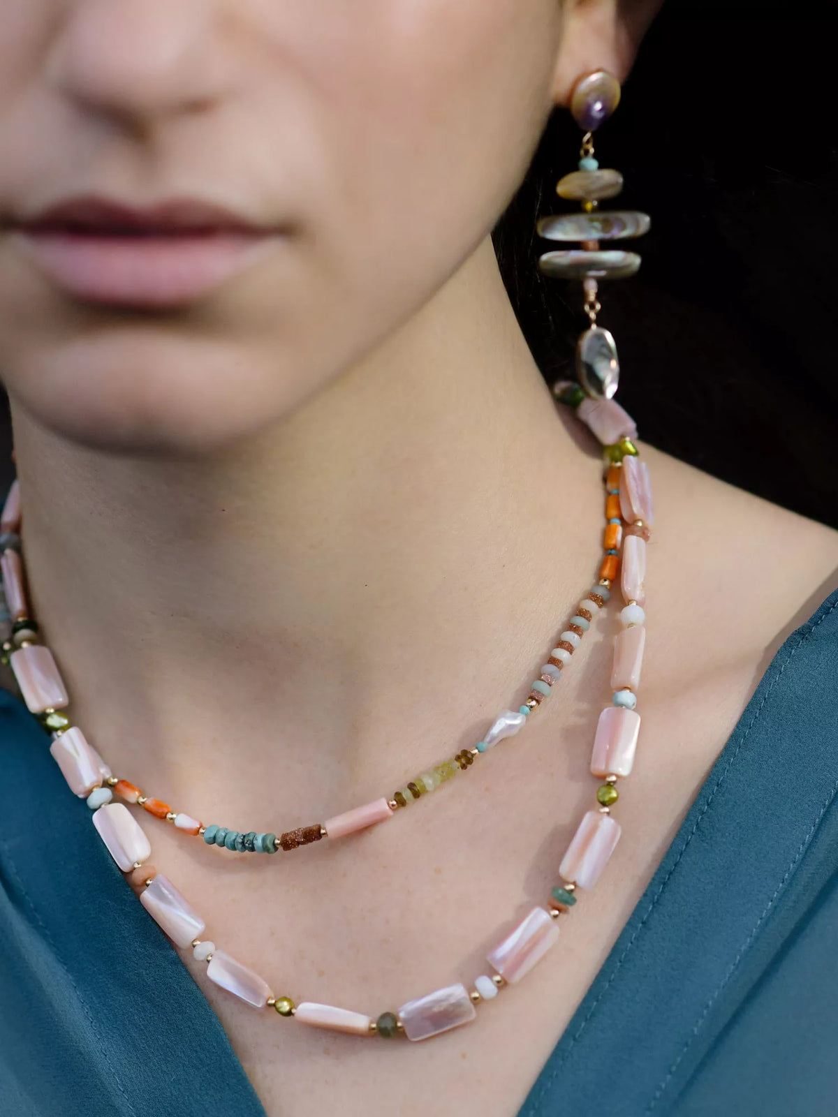 Close-up of a person wearing a beaded necklace and earrings.