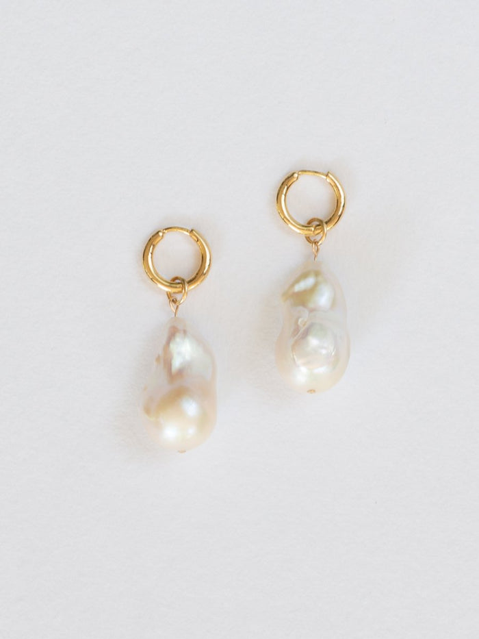 Pair of baroque pearl earrings with gold hooks on a light gray background
