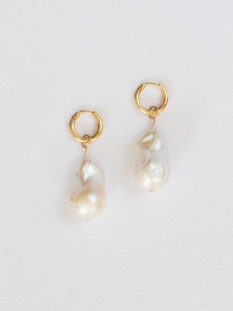 Pair of baroque pearl earrings with gold hooks on a light gray background