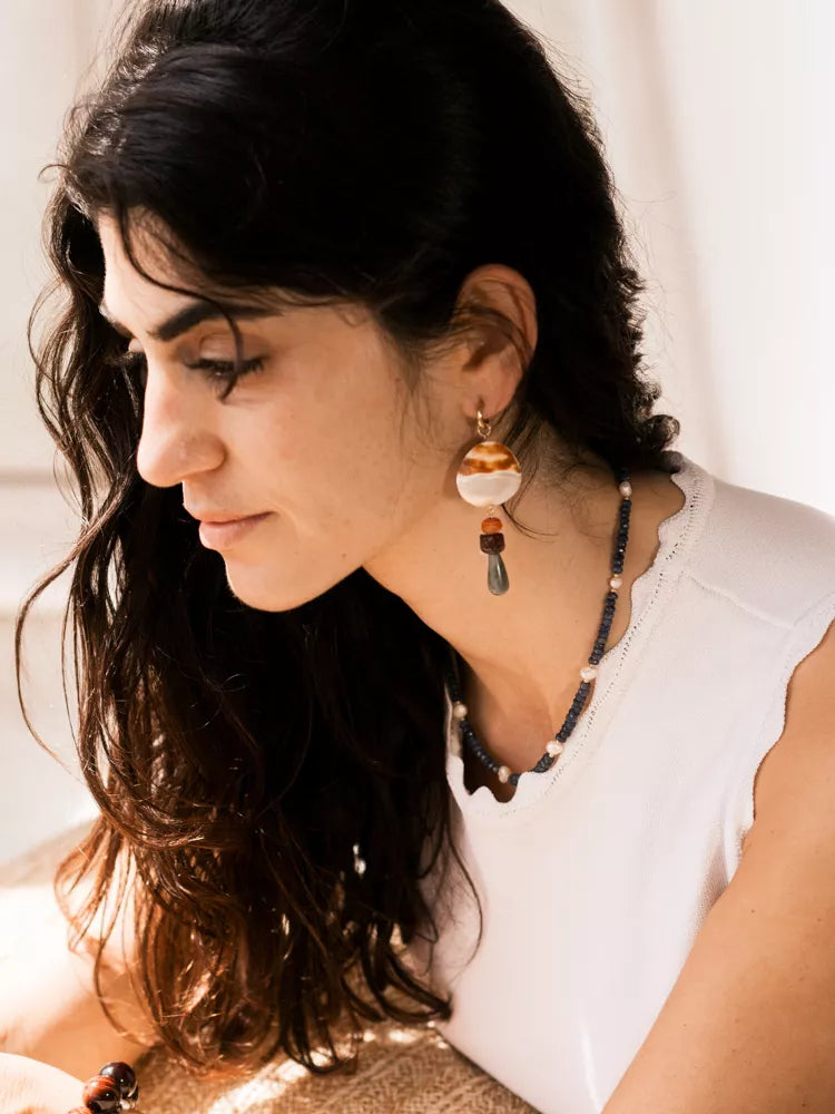 Woman wearing earrings and a necklace with a neutral background