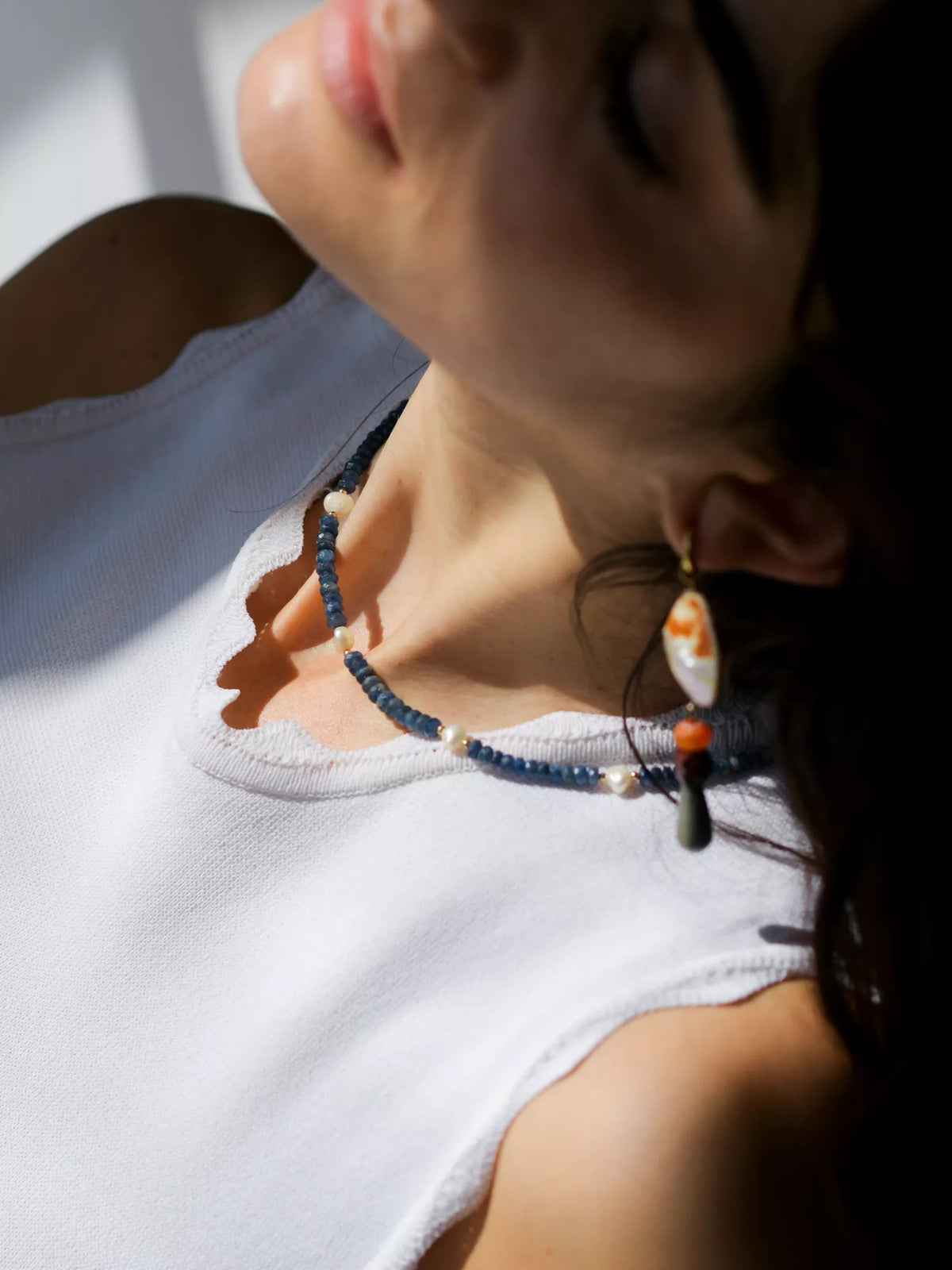 Close-up of a person wearing a beaded necklace and earrings.