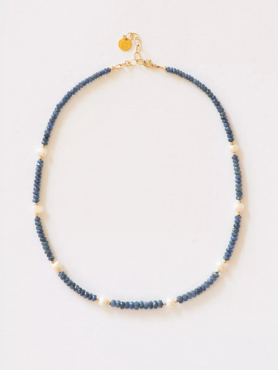 Burmese Sapphire with Station Pearl Necklace flat lay on white background.