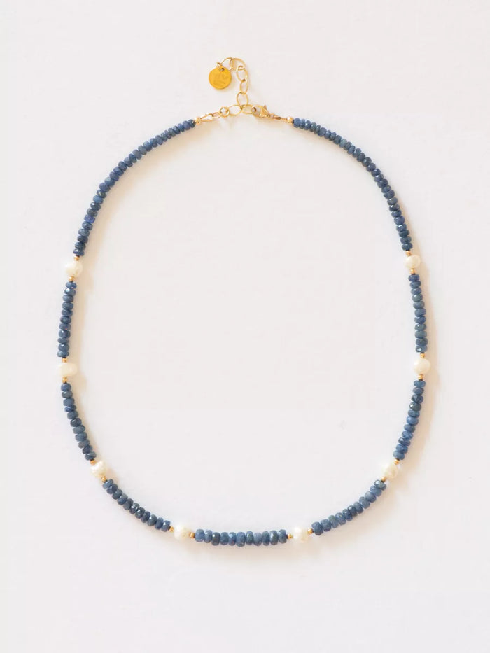 Burmese Sapphire with Station Pearl Necklace flat lay on white background.