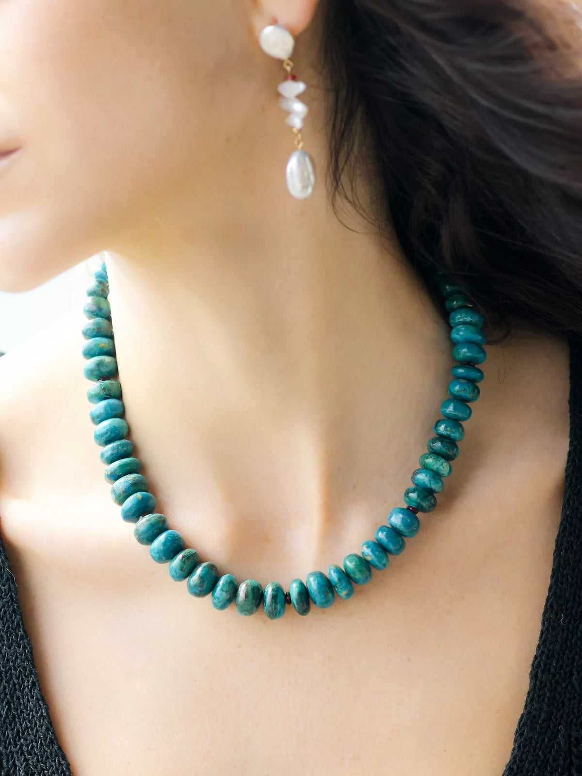 Teal beaded necklace and white pearl earrings on a person