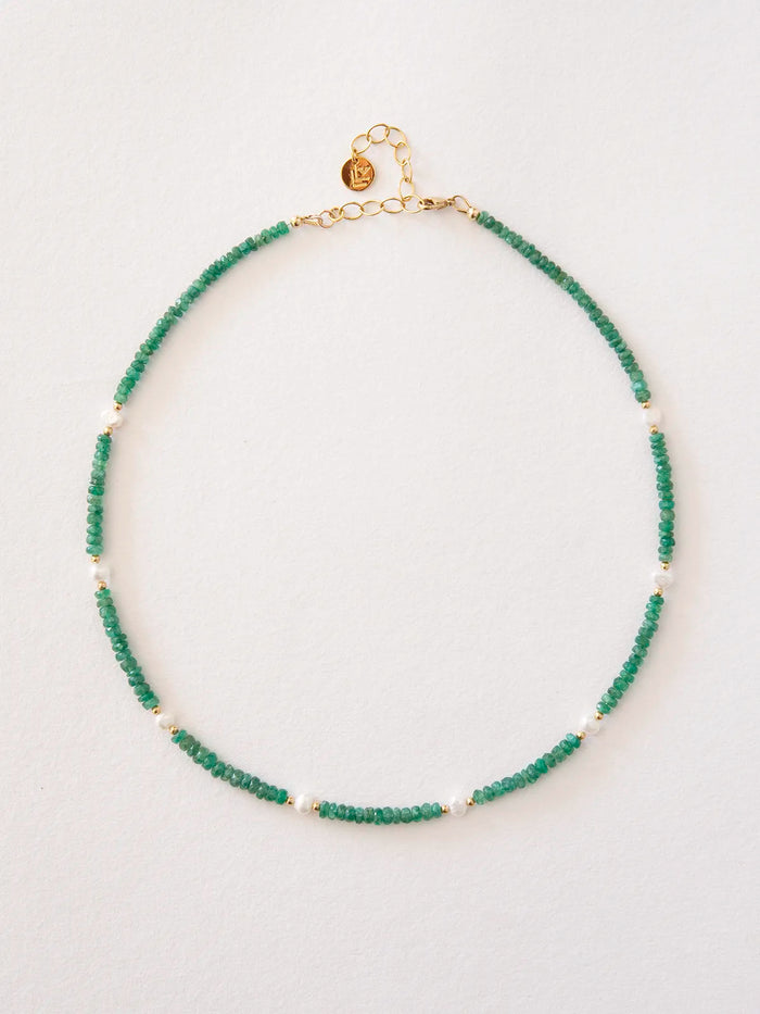 An emerald beaded necklace accented with pearls and solid gold spacer beads, finished with a gold clasp and extender chain, displayed on a clean white background.