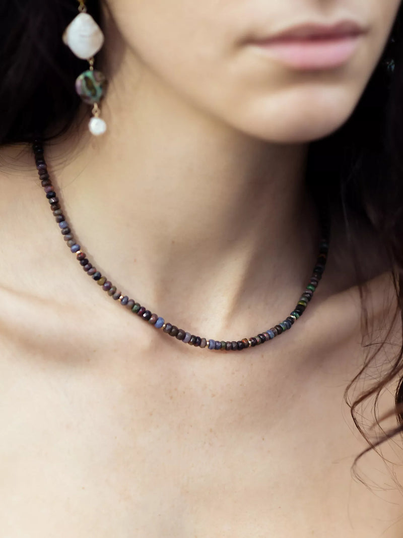 Close-up of a person wearing a beaded necklace and earrings.