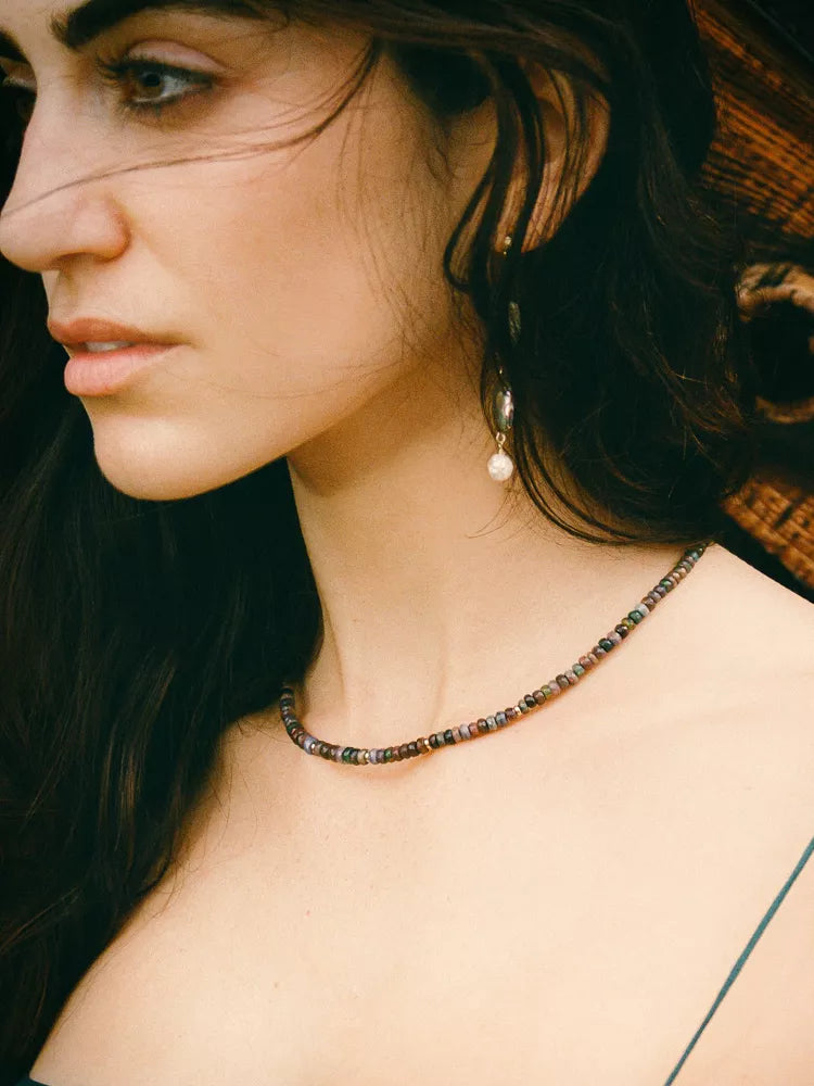 Close-up of a woman wearing a beaded necklace with a neutral background