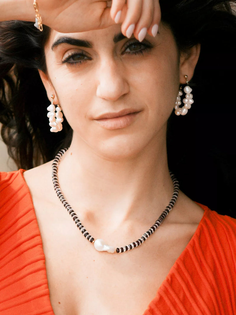 Woman wearing pearl earrings and a necklace with a blurred background