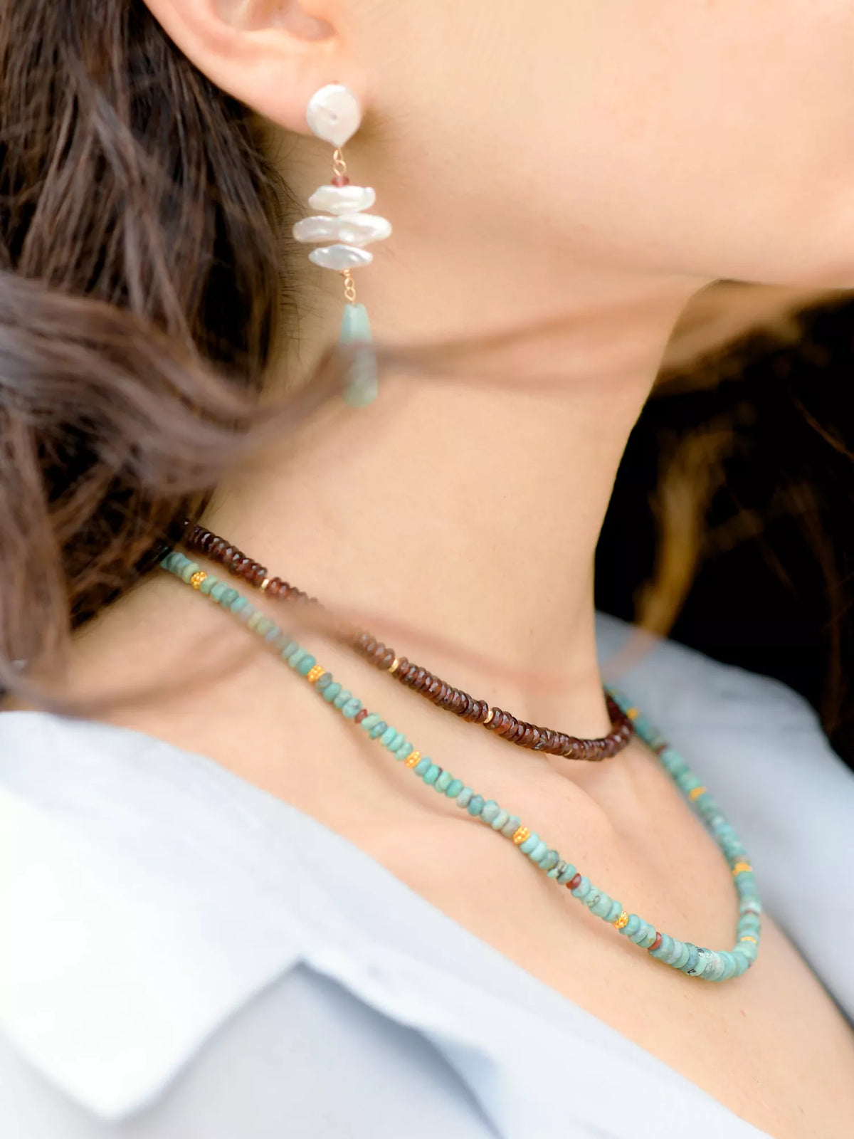 Close-up of a person wearing a beaded necklace and earrings.