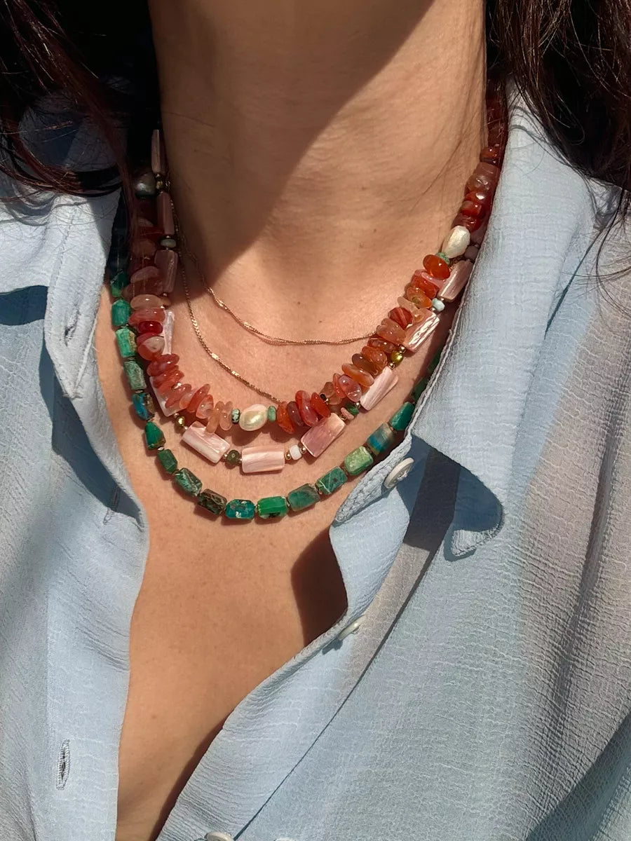Close-up of a person wearing a colorful beaded necklace with a light blue shirt.