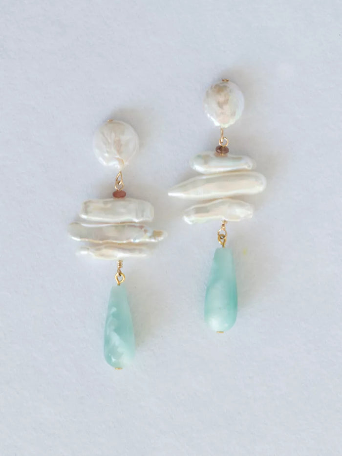 Pair of earrings with layered pearl and green teardrop designs on a light background