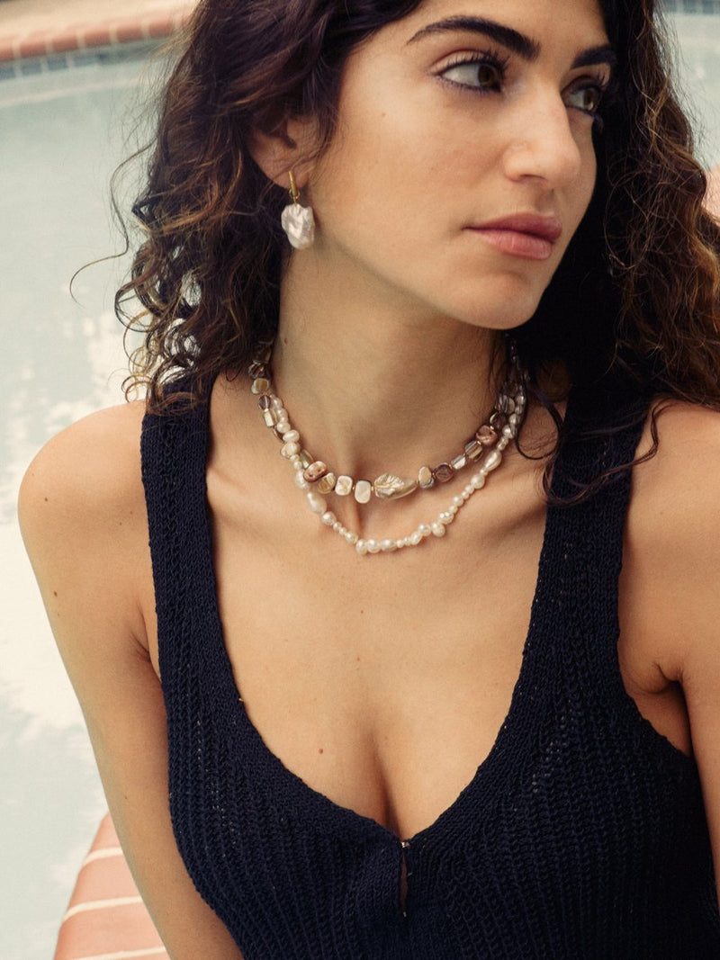 Woman wearing a layered necklace and earrings with a blurred background