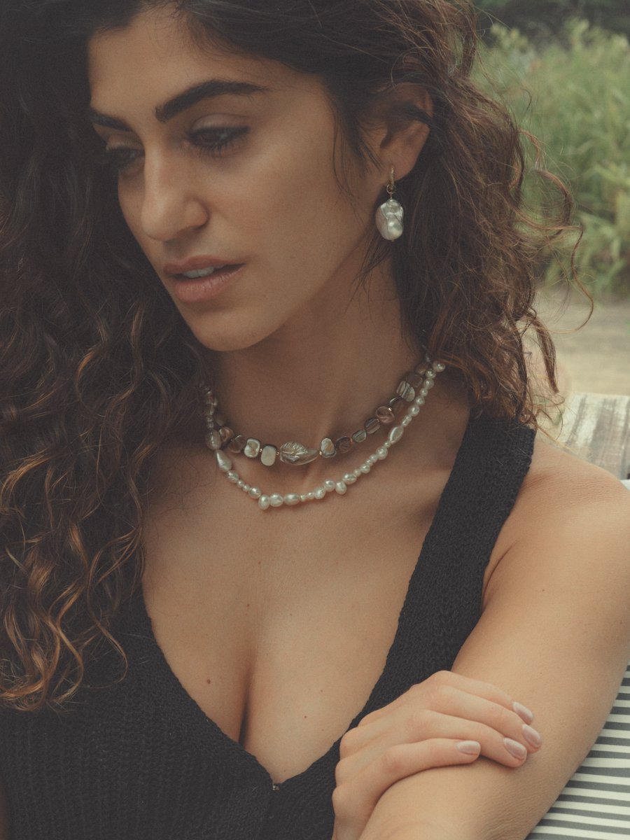 Woman with layered necklaces and earrings outdoors