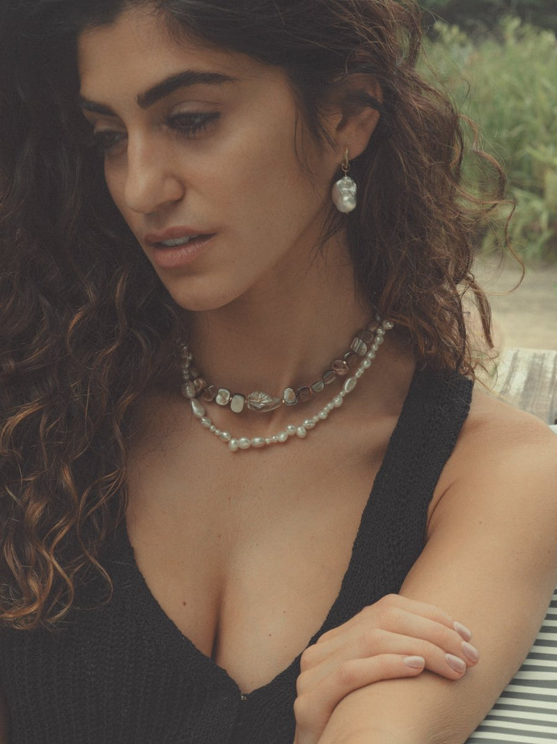 Woman with layered necklaces and earrings outdoors