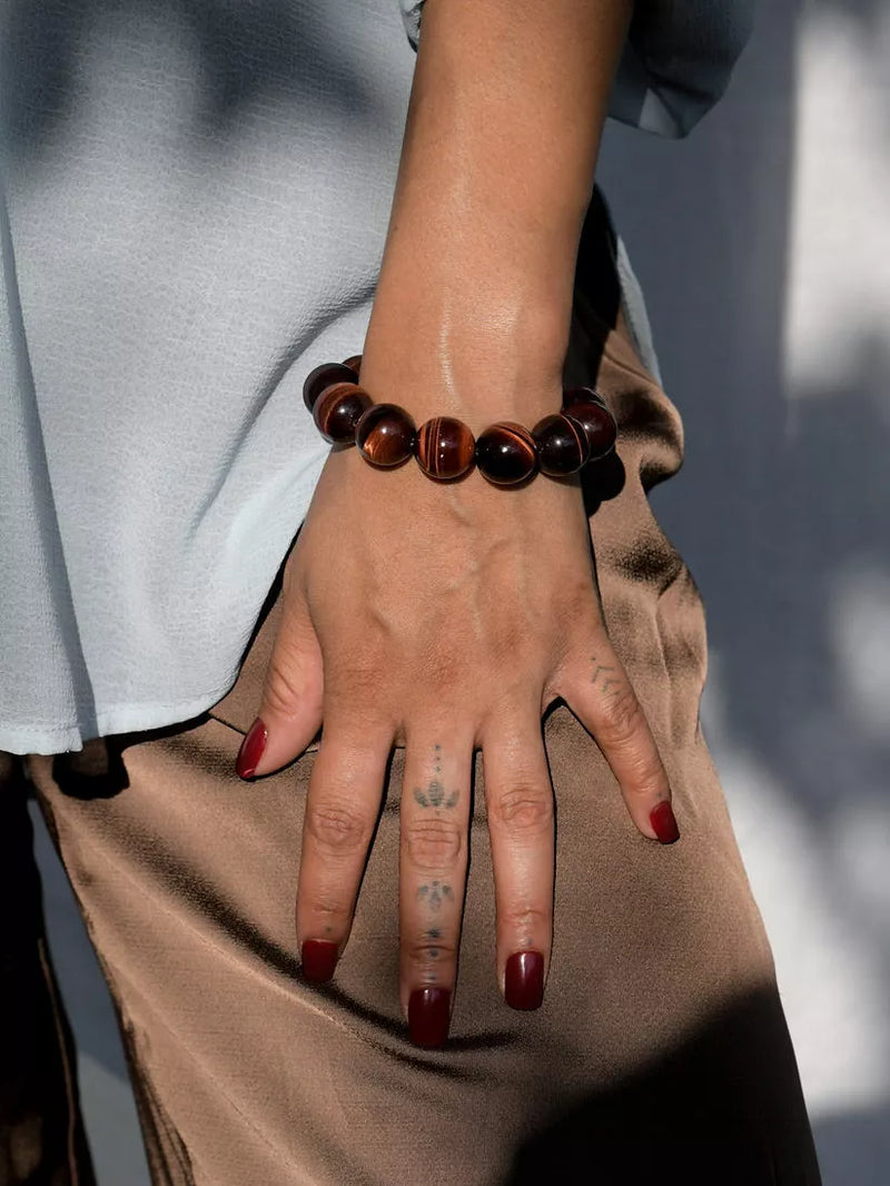 Hand wearing a brown beaded bracelet with a blurred background