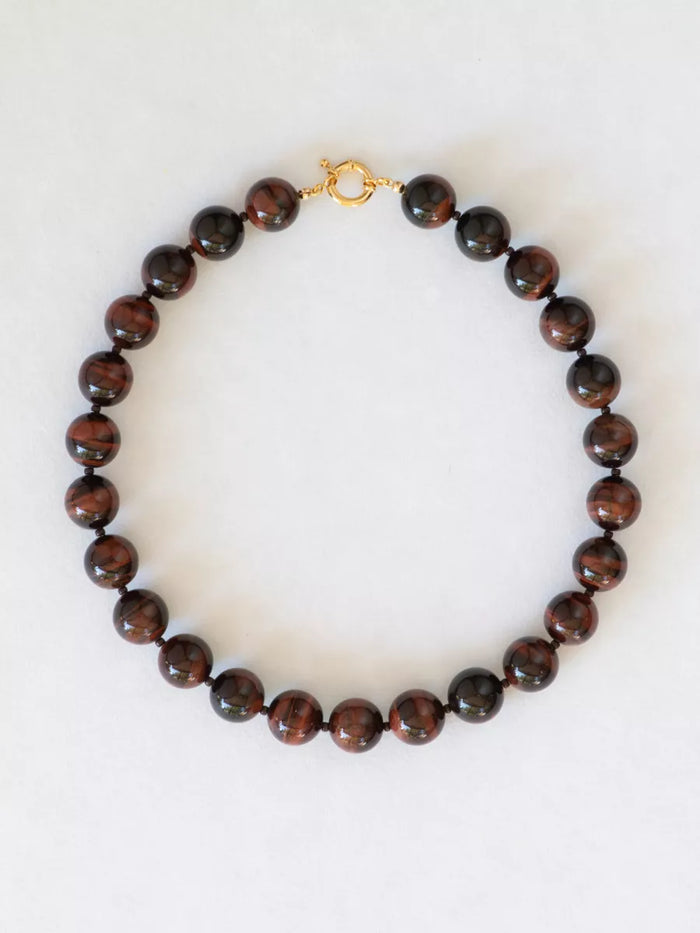 Black cherry tiger's eye necklace with large beads on a white background.