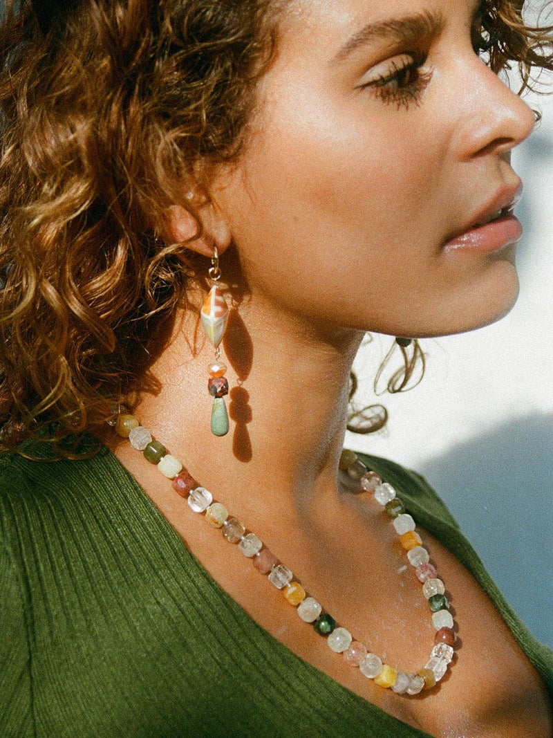 Model wearing a phantom quartz block necklace with shell drop earrings.