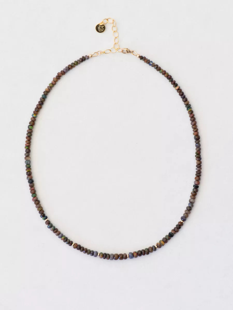 Beaded opal necklace with gold chain on a light gray background.