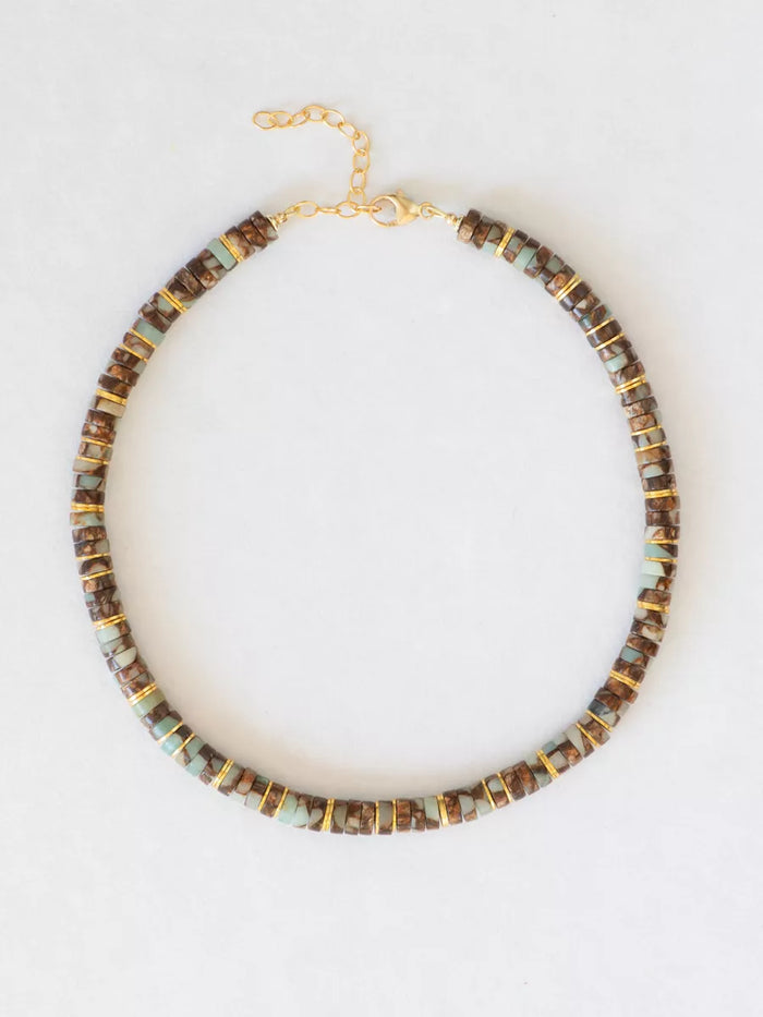 Beaded necklace with gold accents on white background.