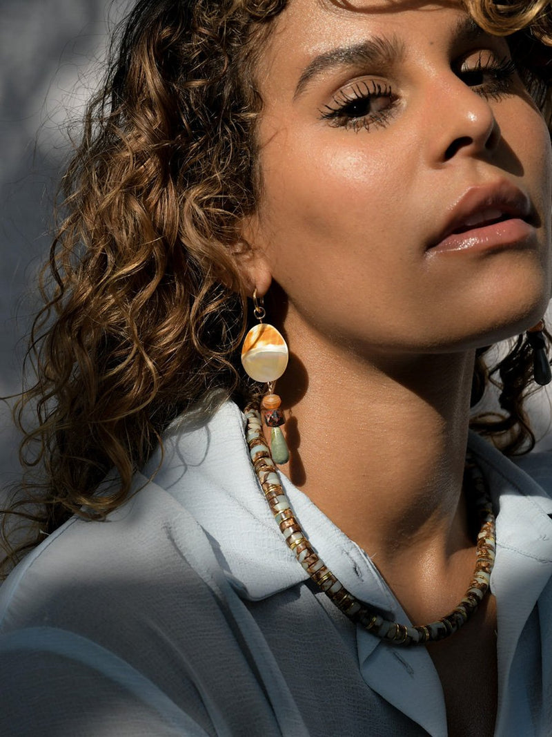 Close-up of a woman wearing a necklace and earrings with a blurred background