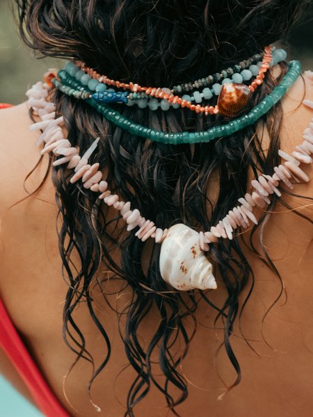 Model with wet hair wearing necklaces backwards