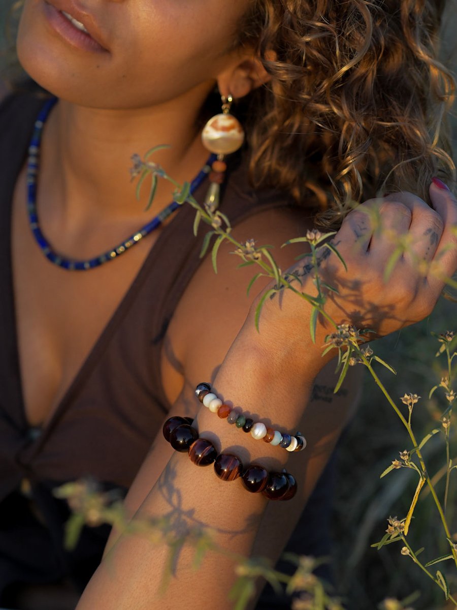 Person wearing a beaded bracelet and necklace with a natural background