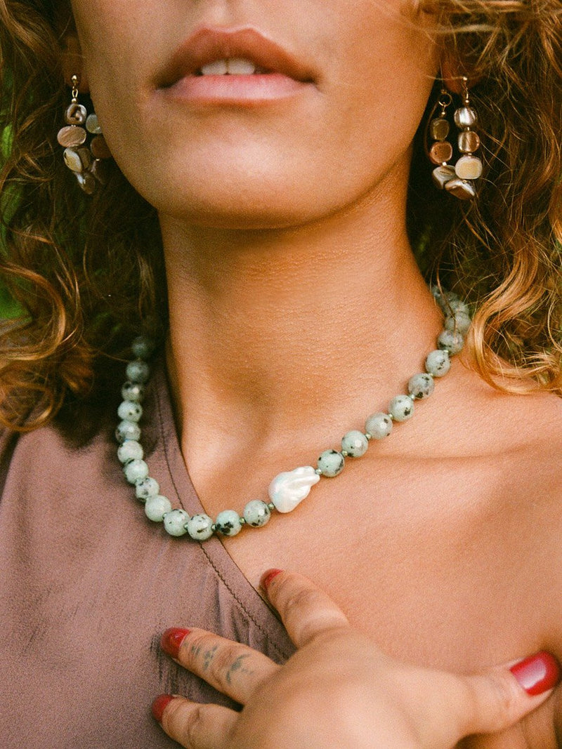 Close up of model wearing seafoam sesame jasper necklace with baroque pearl and nacre nugget ear jacket earrings.