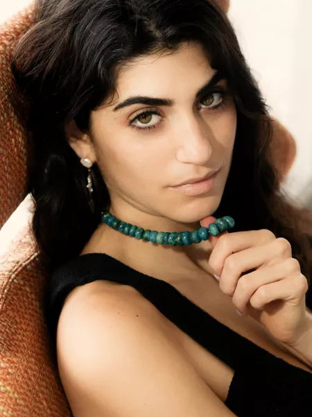 Woman wearing a turquoise beaded necklace against a neutral background