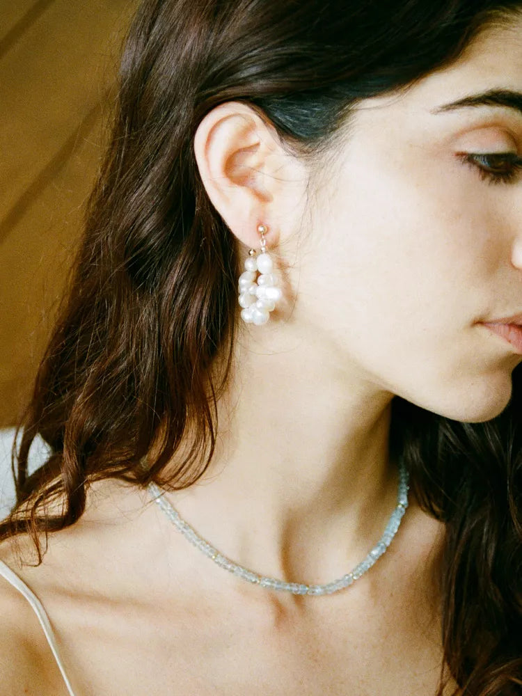 Close-up of a woman wearing pearl earrings and a necklace.