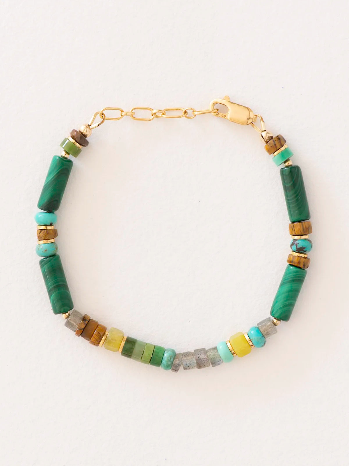 A beaded bracelet with cylindrical green malachite beads and smaller accent beads in turquoise, brown, gray, and yellow, displayed on a clean white background.