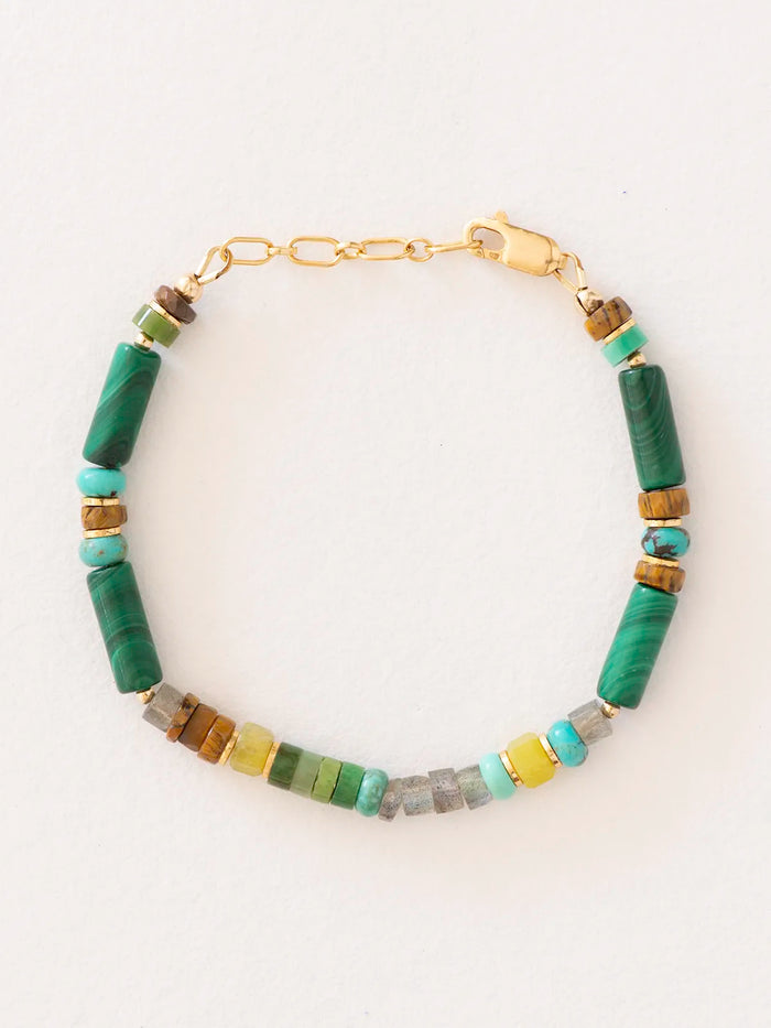 A beaded bracelet with cylindrical green malachite beads and smaller accent beads in turquoise, brown, gray, and yellow, displayed on a clean white background.