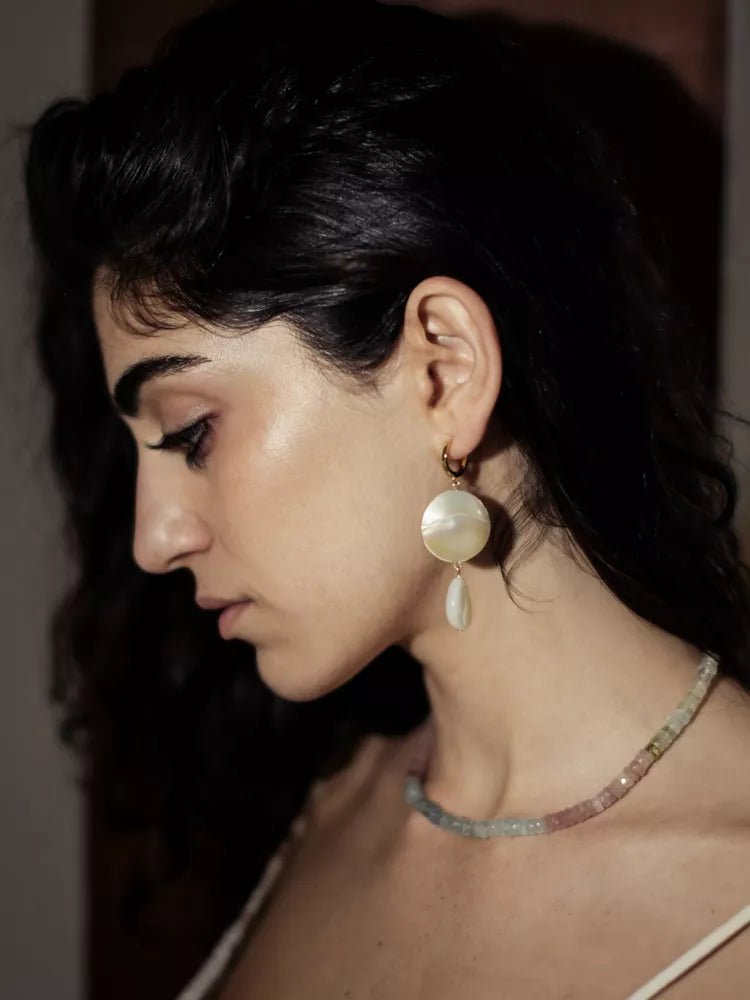 Woman wearing a pearl earring and necklace with a blurred background