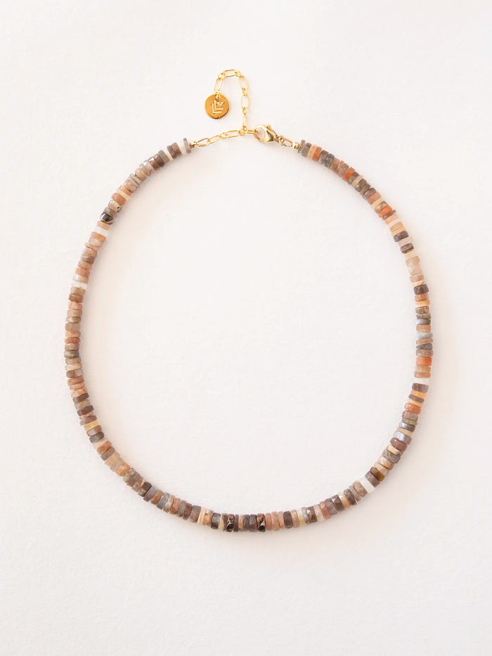 A beaded necklace made of small, irregular stone beads in earthy brown, beige, and gray tones, finished with a gold-filled clasp and chain, shown on a plain white background.