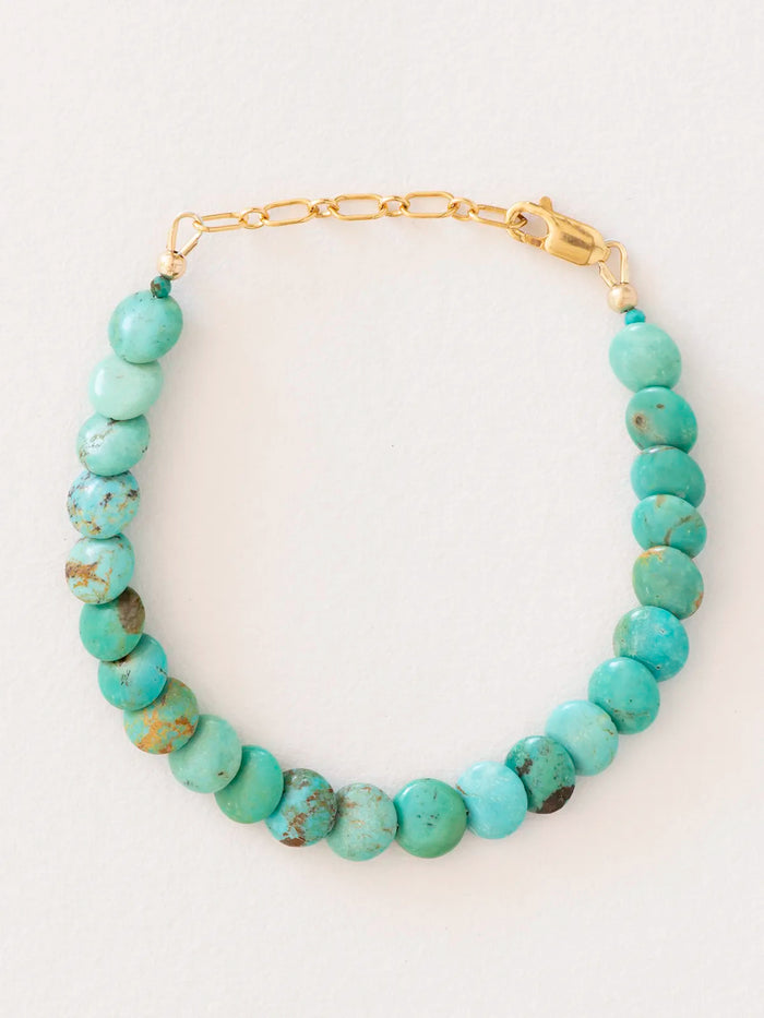 Bracelet made of round turquoise beads connected by a gold-filled chain and clasp, photographed on a plain light background.