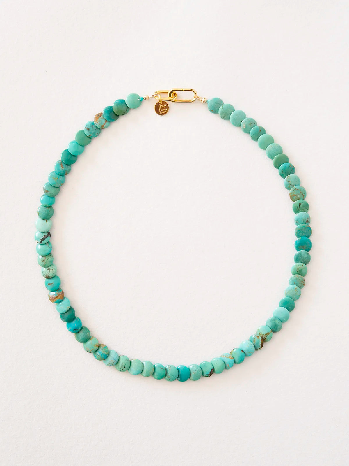 Necklace made of round turquoise beads connected by a gold-filled, reversible clasp, photographed on a plain light background.
