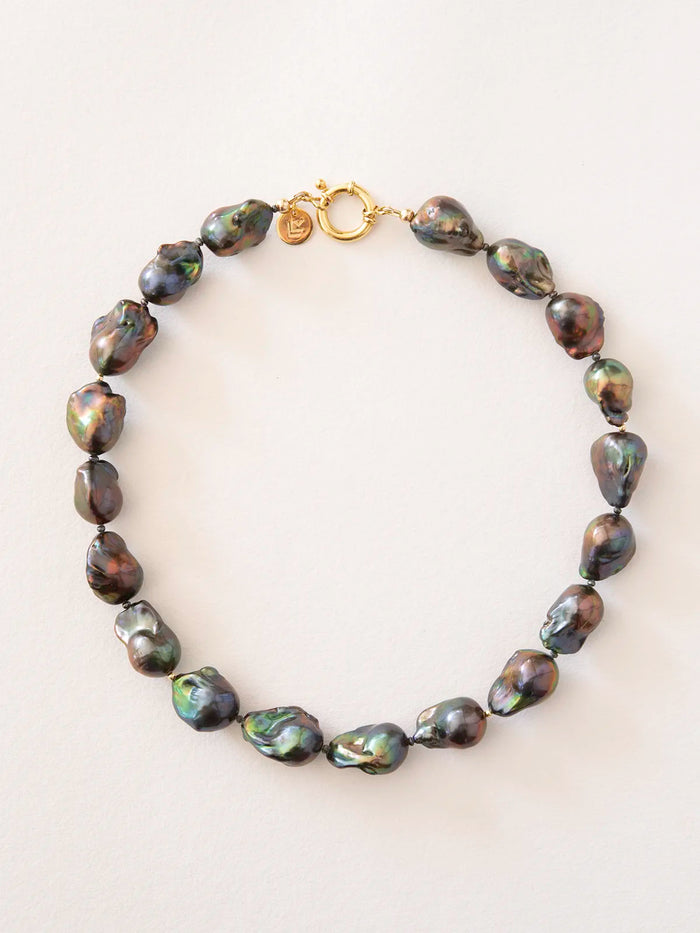 A baroque pearl necklace with an iridescent dark finish and a gold clasp, displayed on a light background.