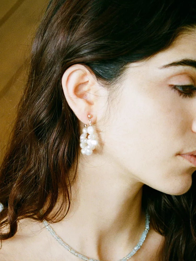 Close-up of a woman wearing pearl earrings with a blurred background