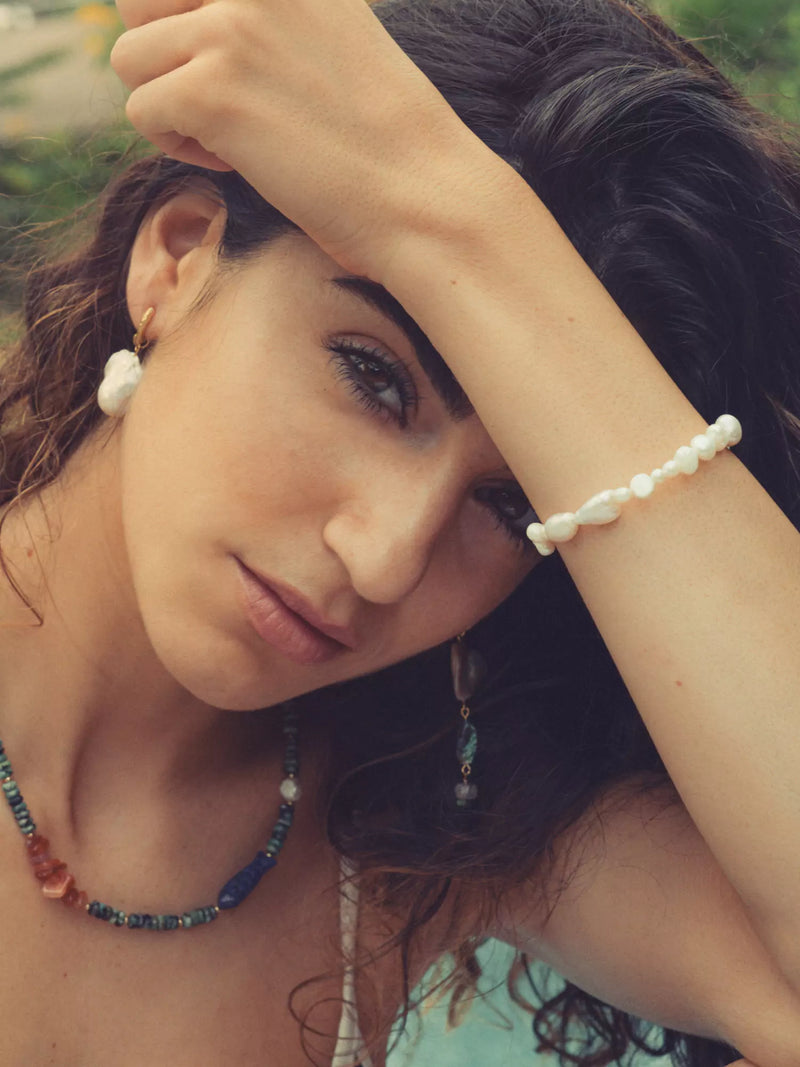 Woman wearing a colorful beaded necklace and bracelet with a blurred natural background