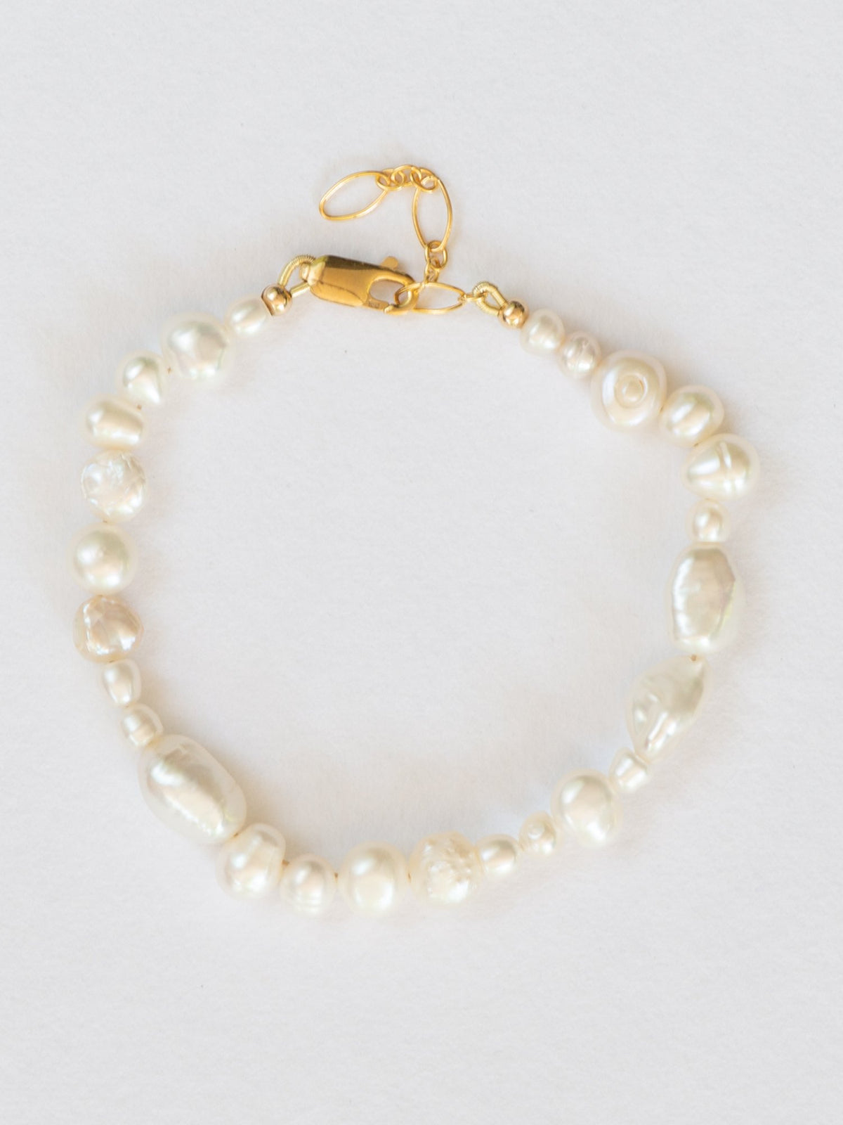Flat lay image of pearl collective bracelet with gold clasp