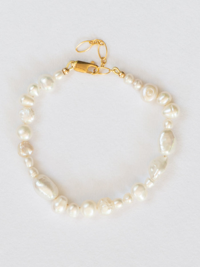 Flat lay image of pearl collective bracelet with gold clasp