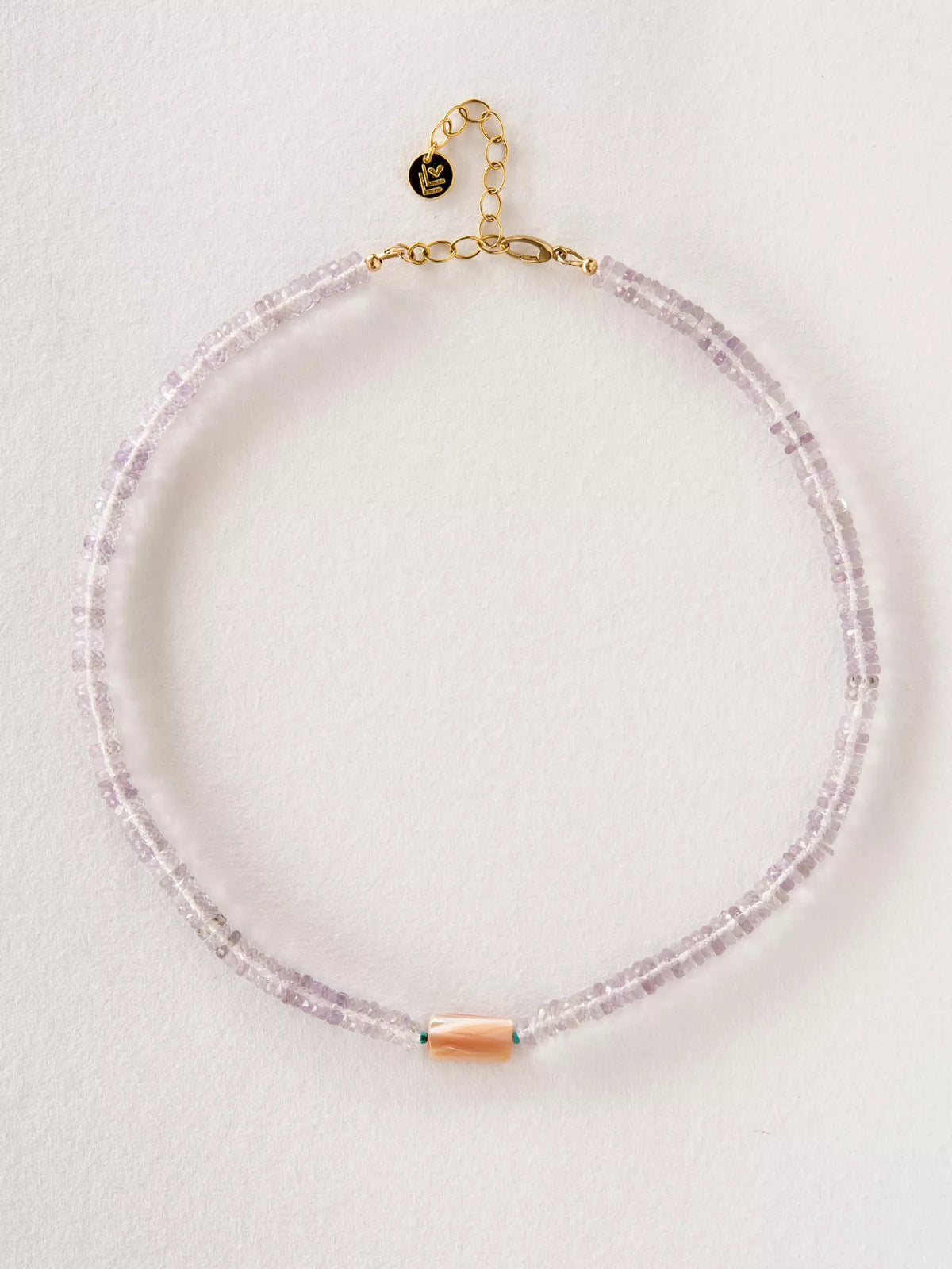 Necklace with pink beads and gold clasp on a light gray background