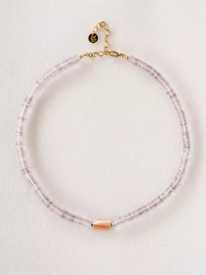 Necklace with pink beads and gold clasp on a light gray background