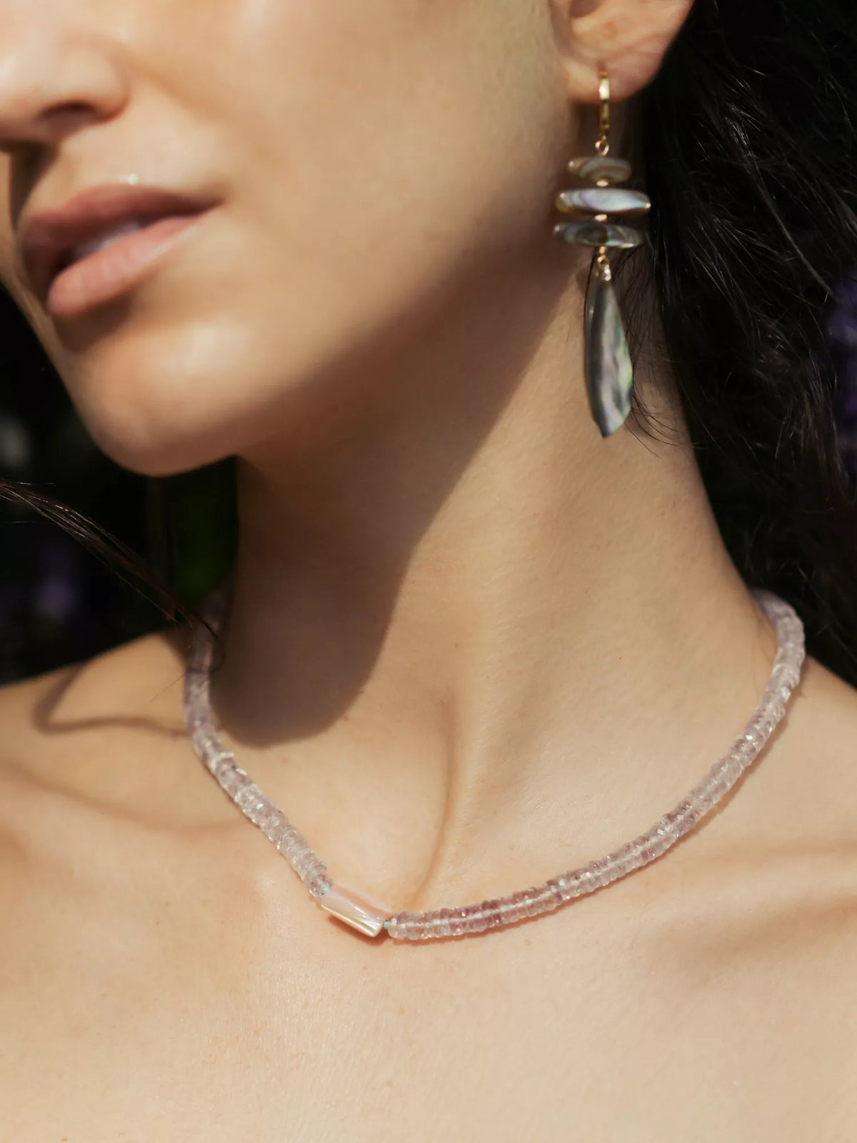 Close-up of a woman wearing a necklace and earrings with a blurred background