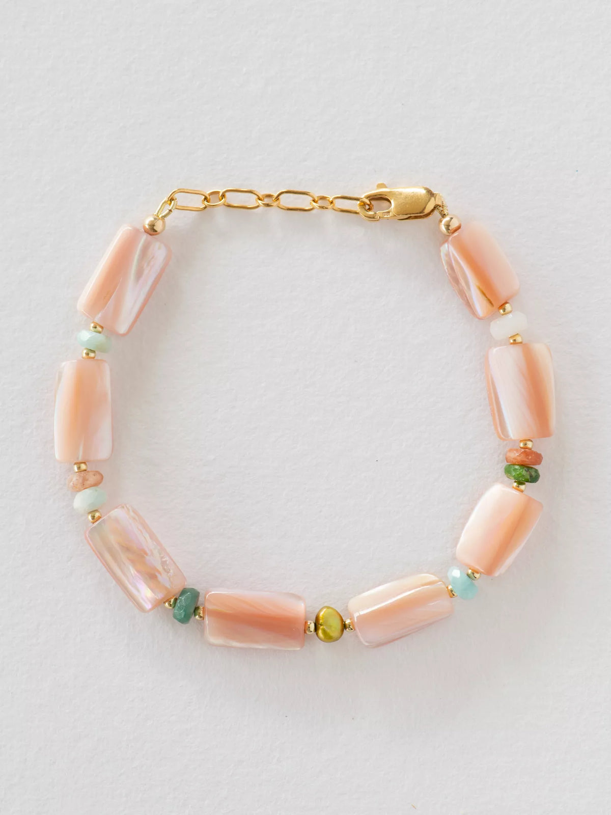 Bracelet with pink beads and gold chain on a light gray background