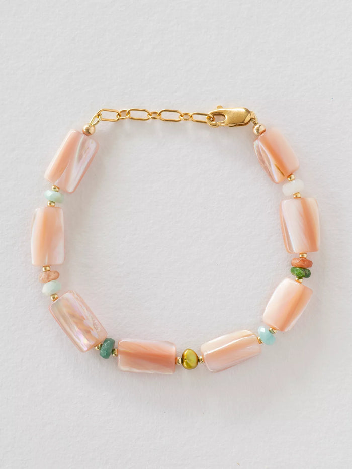 Bracelet with pink beads and gold chain on a light gray background