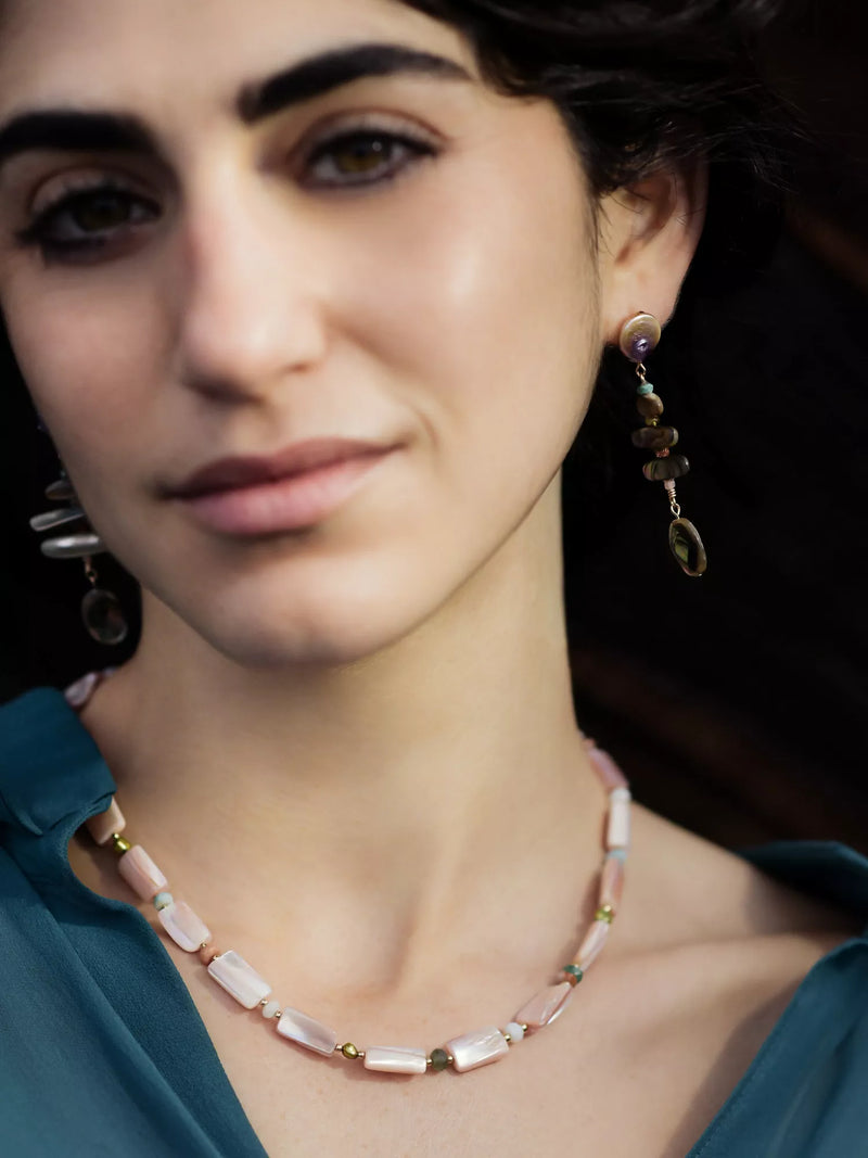 Close-up of a woman wearing a necklace and earrings with a dark background